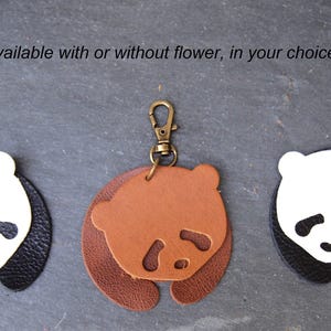 May include: Three leather panda keychains with a metal ring. One keychain is black and white with a purple flower, one is brown and white, and one is black and white.
