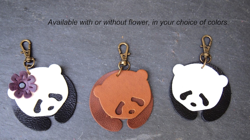 May include: Three leather panda keychains with a metal ring. One keychain is black and white with a purple flower, one is brown and white, and one is black and white.