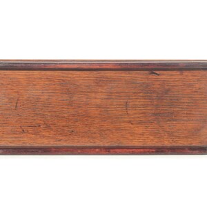 Puede incluir: Bandeja rectangular de madera para servir con acabado marr&oacute;n oscuro. La bandeja tiene un borde elevado y asas integradas en cada extremo. La veta de la madera es visible. Una pieza sencilla y funcional para servir.