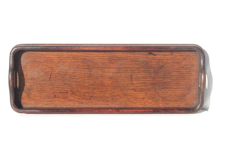 Puede incluir: Bandeja rectangular de madera para servir con acabado marr&oacute;n oscuro. La bandeja tiene un borde elevado y asas integradas en cada extremo. La veta de la madera es visible. Una pieza sencilla y funcional para servir.