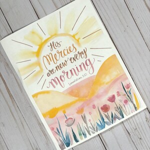 May include: Watercolor painting of a sunrise over a field of flowers with the quote "His mercies are new every morning" and the scripture reference "Lamentations 3:23".