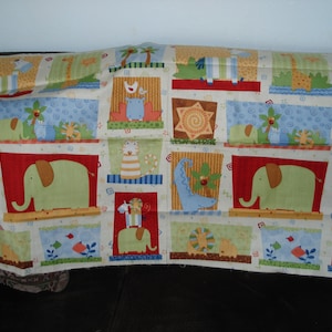 May include: A colorful fabric with a repeating pattern of animals, including elephants, giraffes, and lions. The fabric is in a patchwork style with squares and rectangles of different colors and patterns.