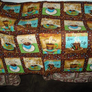 May include: A brown fabric with a repeating pattern of coffee cups on squares. Each square features a different coffee cup design with the words "Coffee", "Mocha", and "House Blend". The background is dotted.