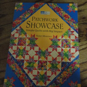 May include: A book titled "Patchwork Showcase" with the subtitle "Simple Quilts with Big Impact" by Nancy Mahoney. The cover features a colorful patchwork design with a yellow diamond shape in the center and a blue border.