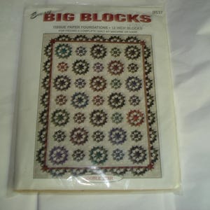 May include: A package for a quilt pattern titled "Big Blocks." The pattern features a design of star-shaped blocks, each approximately 12 inches. The quilt design includes various colors, including green, blue, and red.