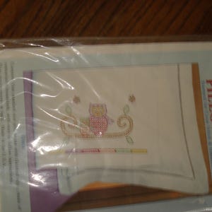 May include: A white pillowcase with an embroidered owl design in pink, yellow, and green. The pillowcase is packaged in a plastic bag with the text "Children's Pillowcase" and "Stamped for the Free-Stitch" printed on the front.