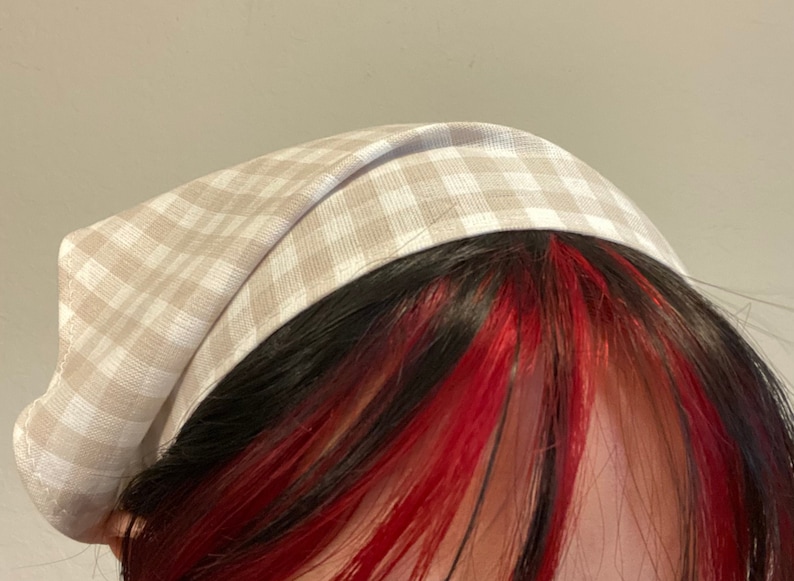 Pu&ograve; includere: Un cerchietto per capelli in tessuto a quadri beige e bianco.