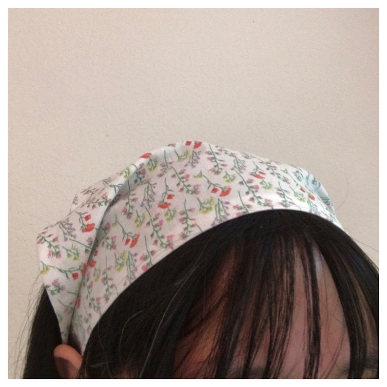 Pu&ograve; includere: Un cerchietto bianco con un motivo floreale con piccoli fiori rossi, rosa e gialli. Il cerchietto &egrave; realizzato in un tessuto morbido e si lega dietro la testa.