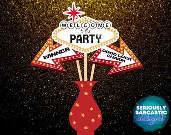 May include: A red and white Vegas-style sign with the text "Welcome to the Party" in a black font.  Two red and white arrow signs with the text "Winner" and "Good Luck Charm" are on either side of the sign.  The signs are in front of a gold glitter background.