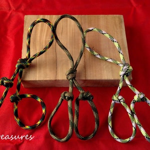 May include: Three handmade rope halters in the image, each with a unique color pattern. The halters are knotted and looped, with a wooden block in the background. The rope colors include black, yellow, green, and white. The background is red.