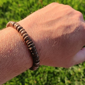 May include: A brown wooden beaded bracelet with a natural wood grain pattern.