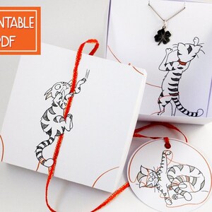 May include: Printable PDF template for a gift box with a cat illustration and a red ribbon. The box is decorated with a cat illustration and the text "Printable PDF".