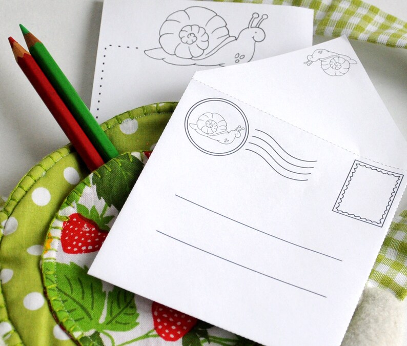 Puede incluir: Un sobre blanco con un dise&ntilde;o de caracol y un espacio en blanco para escribir un mensaje. El sobre tiene un sello con un dise&ntilde;o de caracol y un espacio en blanco para un sello. El sobre est&aacute; sobre una tela verde y blanca con lunares blancos.
