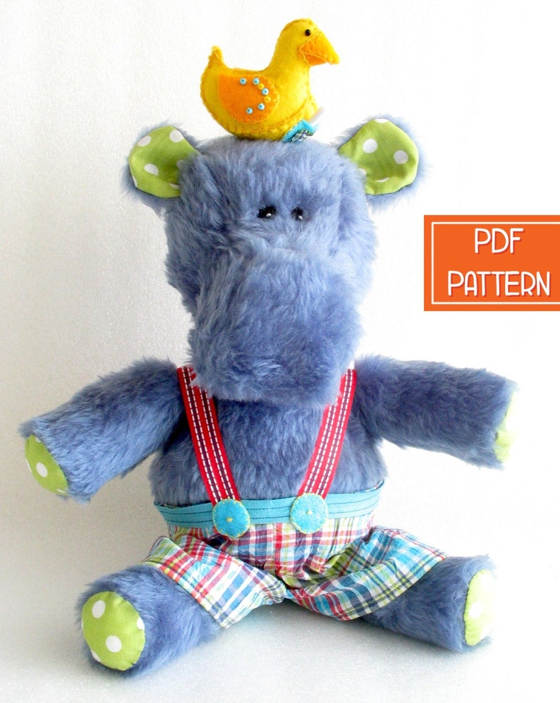 May include: A blue plush toy hippopotamus wearing red suspenders and plaid pants. The hippo has green and white polka dot ears and a yellow rubber duck on its head.  PDF PATTERN.