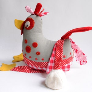 May include: A gray fabric chicken toy with red and white polka dot fabric accents. The chicken has a yellow beak, red felt eyes, and a red felt tail.