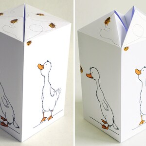 May include: A white paper box with a goose design and a blue butterfly on the front. The box is folded flat and has a flap that can be lifted to reveal the inside. The box is decorated with small orange butterflies.