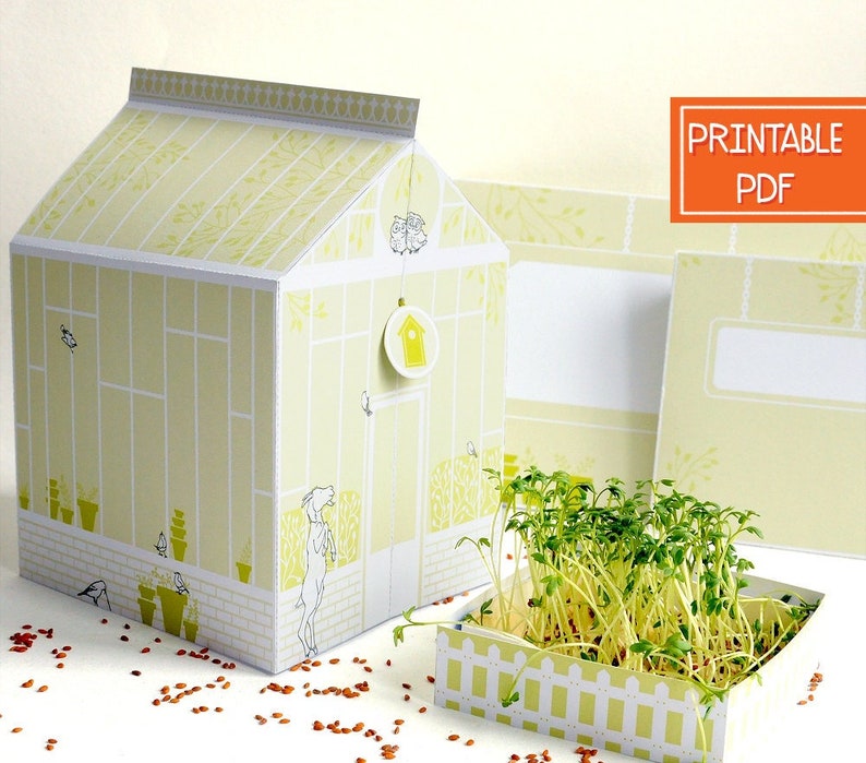 May include: Printable PDF template for a paper greenhouse with a small white picket fence and a green plant growing inside. The greenhouse is decorated with a yellow and white pattern and has a small birdhouse on the side.