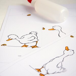 May include: A white sheet of paper with a black and white illustration of a duck. The duck is looking down at a small yellow bug. The paper is folded in half and there is a bottle of glue on top of the paper.