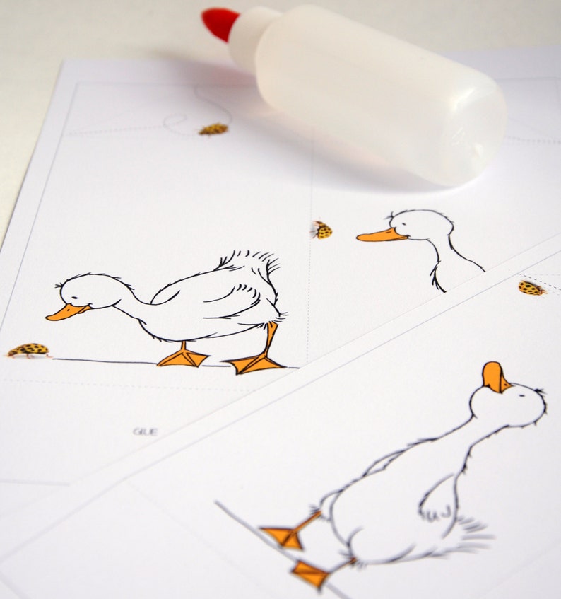 May include: A white sheet of paper with a black and white illustration of a duck. The duck is looking down at a small yellow bug. The paper is folded in half and there is a bottle of glue on top of the paper.