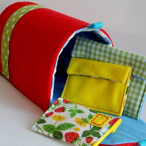 Puede incluir: Un buz&oacute;n de fieltro rojo con una cinta de lunares verde y blanco. El buz&oacute;n est&aacute; abierto y tiene varios sobres de fieltro de colores en su interior.