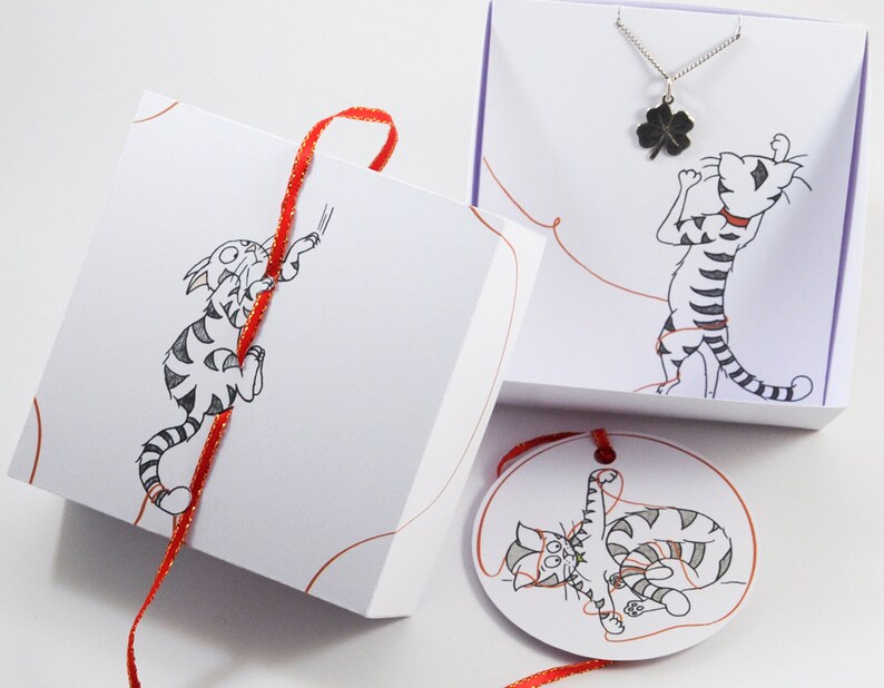 May include: A white gift box with a red ribbon and a black and white illustration of a cat. The box is tied with a red ribbon and has a small tag with a black and white illustration of a cat on it. The tag is attached to the ribbon with a red string.