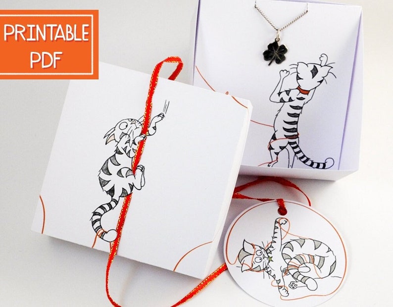 May include: Printable PDF template for a gift box with a cat illustration and a red ribbon. The box is decorated with a cat illustration and the text "Printable PDF".