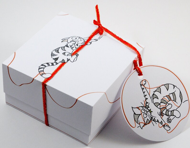May include: A white gift box with a red ribbon and a cat illustration. The box has a round tag attached with a cat illustration and the text "The Cat's Meow".