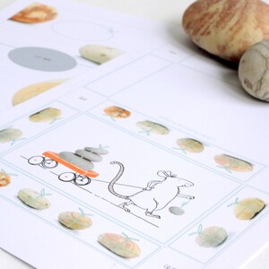 May include: A black and white illustration of a mouse pulling a red wagon with a stack of gray stones. The wagon has two wheels and a handle. The mouse has a long tail and is wearing a bow tie. The illustration is surrounded by a border of small gray stones.