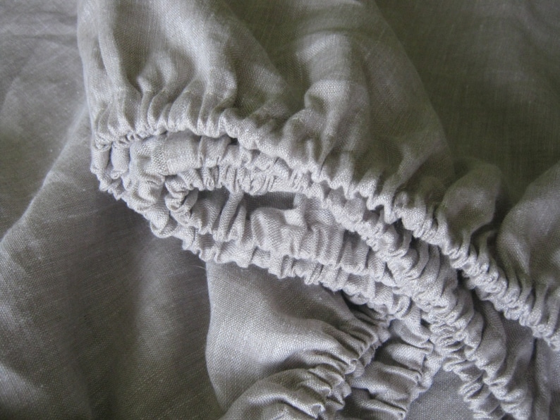 Close-up of the elastic edge of an oatmeal linen fitted sheet
