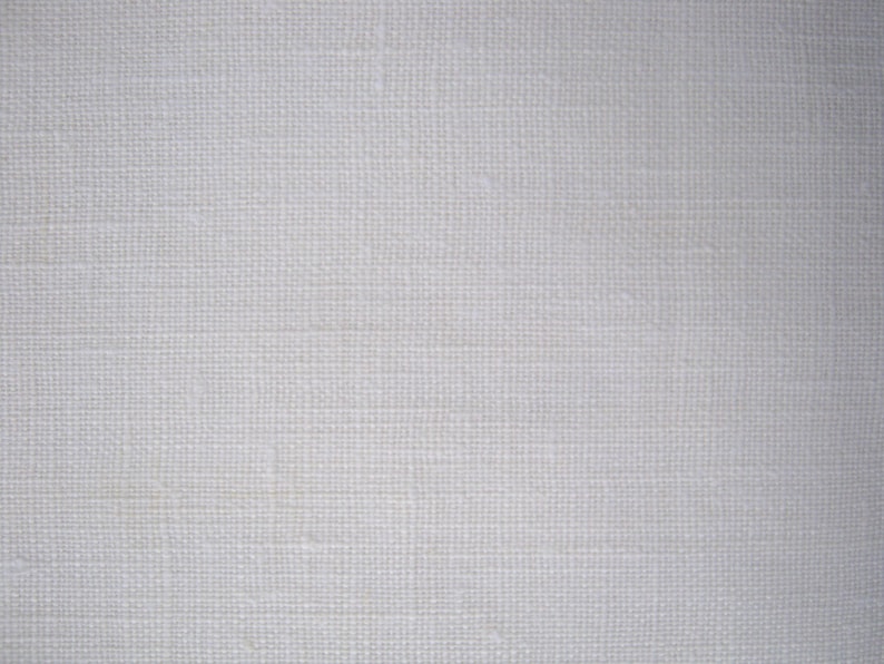 Puede incluir: Primer plano de una tela blanca tejida con una textura sutil. La tela tiene una superficie lisa y uniforme y un color ligeramente blanquecino.