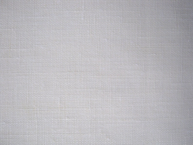 May include: A close-up of a white woven fabric with a subtle texture. The fabric has a smooth, even surface and a slightly off-white color.