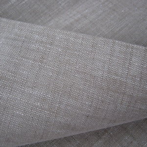 Puede incluir: Primer plano de una tela de lino natural con un tejido texturizado. La tela es de color beige claro.
