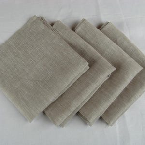 Four oatmeal linen napkins fanned out on a white table