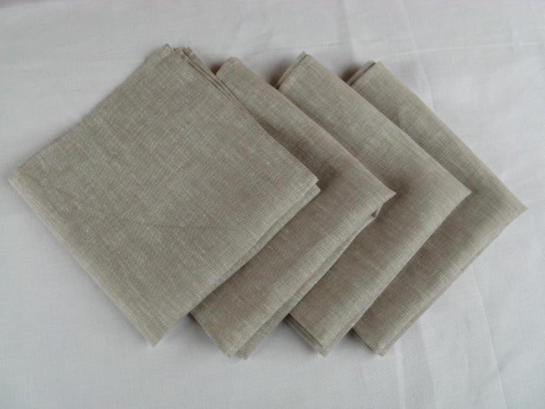 Four oatmeal linen napkins fanned out on a white table