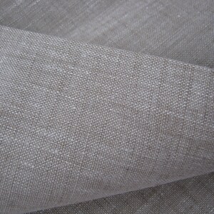 May include: Close-up of a natural linen fabric with a textured weave. The fabric is a light beige color and has a slightly rough feel.
