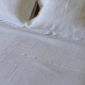 May include: White linen bedding with a flat sheet and two pillowcases. The bedding is smooth and wrinkle-free.