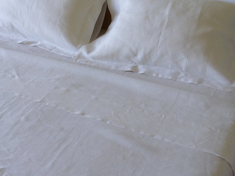 May include: White linen bedding with a flat sheet and two pillowcases. The bedding is smooth and wrinkle-free.
