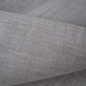 May include: Close-up of a natural linen fabric with a textured weave. The fabric is a light beige color and has a slightly rough feel.