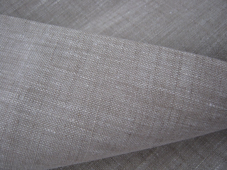 May include: Close-up of a natural linen fabric with a textured weave. The fabric is a light beige color and has a slightly rough feel.
