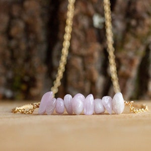 May include: A delicate gold chain necklace with a row of light pink and white gemstone beads.