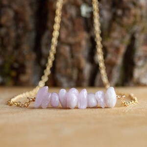 May include: A delicate gold chain necklace with a bar of light pink and white stones.