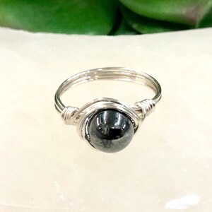 May include: A silver wire wrapped ring with a black hematite gemstone.