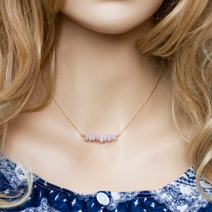 May include: A delicate gold chain necklace with a bar of light pink stones.