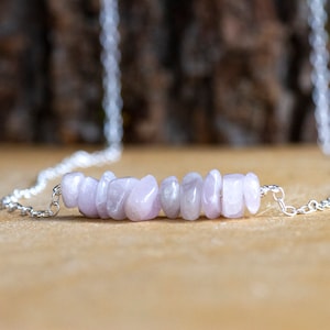 May include: A silver chain necklace with a row of light purple gemstone chips.