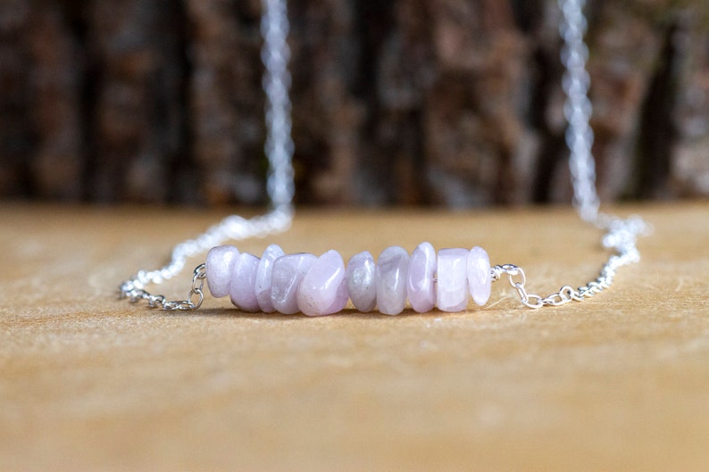 May include: A silver chain necklace with a row of light purple gemstone chips.