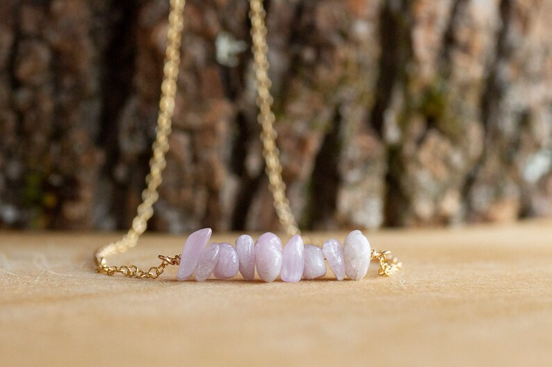 May include: A delicate gold chain necklace with a row of pale lavender gemstone chips.