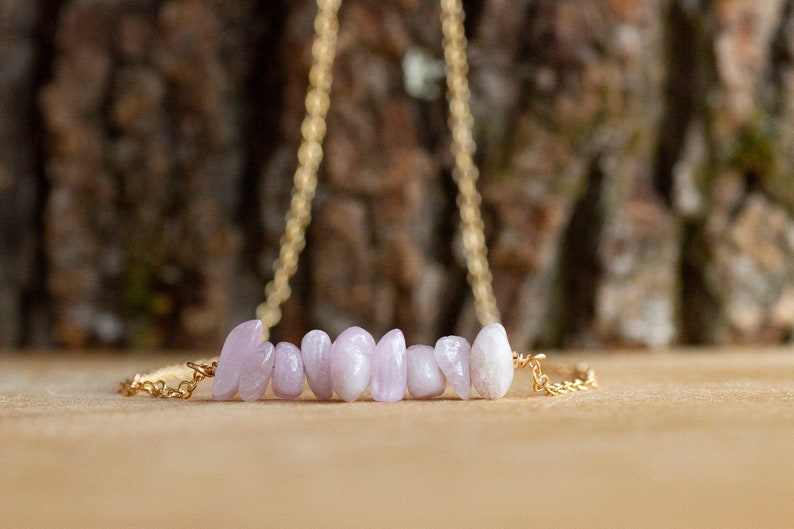 May include: A delicate gold chain necklace with a row of light pink and white gemstone beads.