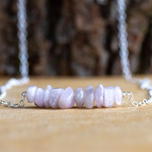 May include: A silver chain necklace with a delicate row of light purple gemstone chips.