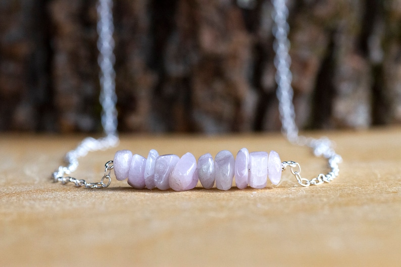 May include: A silver chain necklace with a delicate row of light purple gemstone chips.