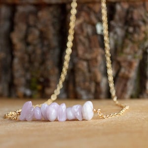May include: A delicate gold chain necklace with a row of light purple and white gemstone chips.